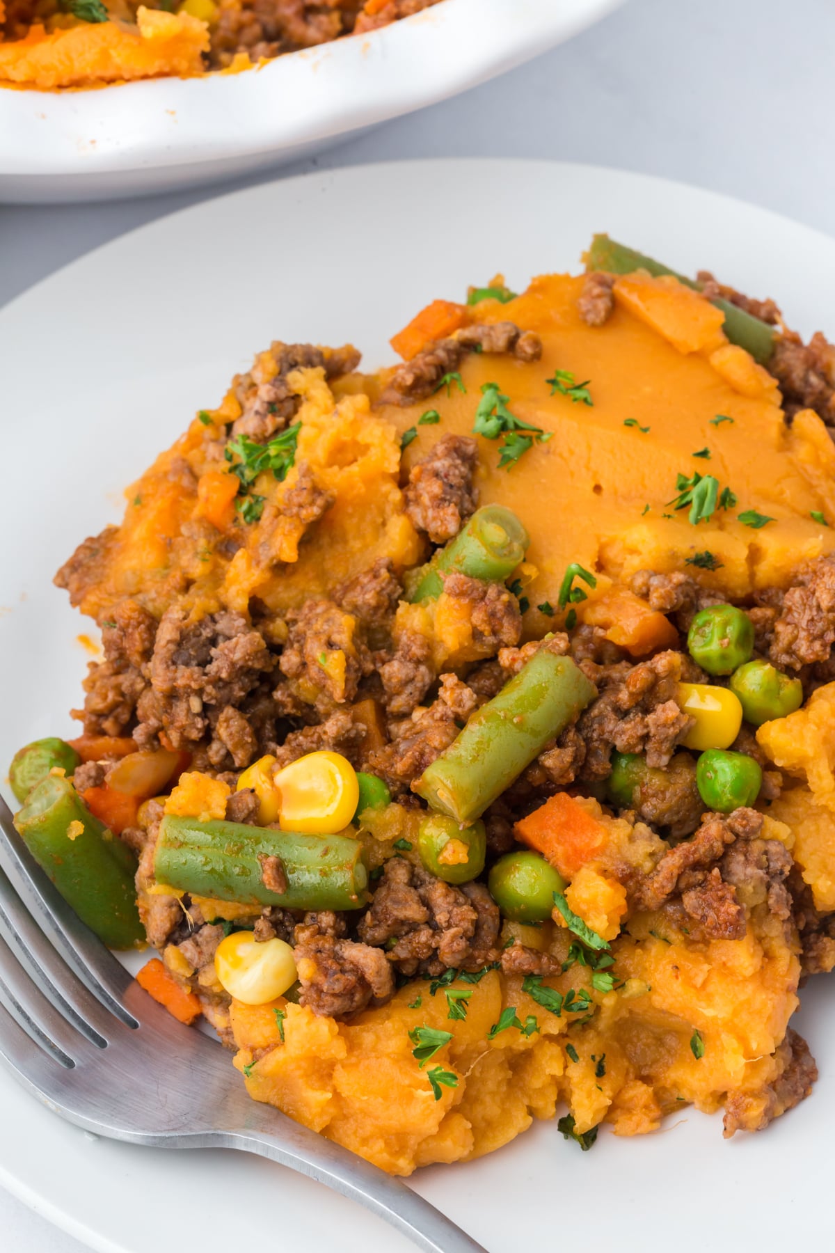 Shepherd's pie with sweet potatoes on a plate with a fork on the side.