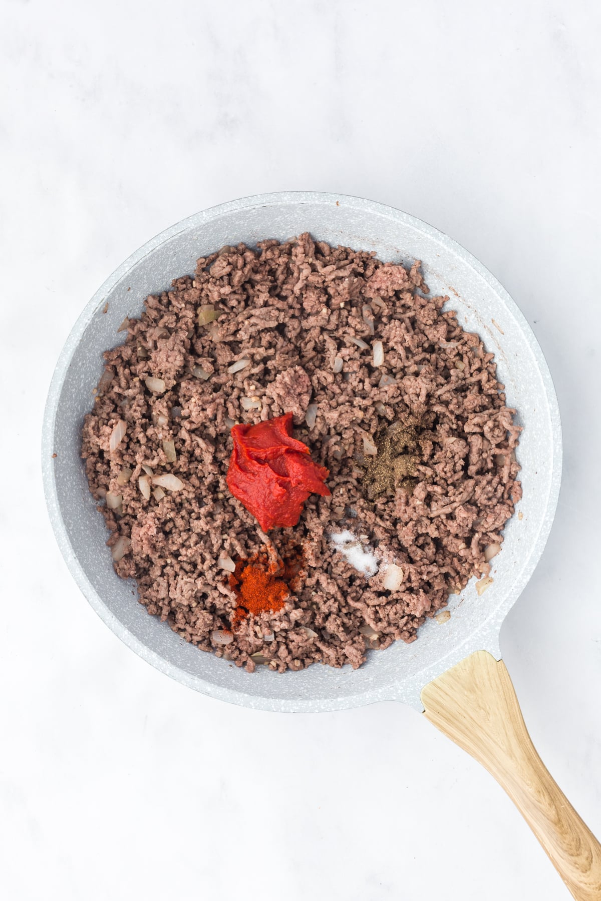 Tomato paste and seasonings added to the pan.