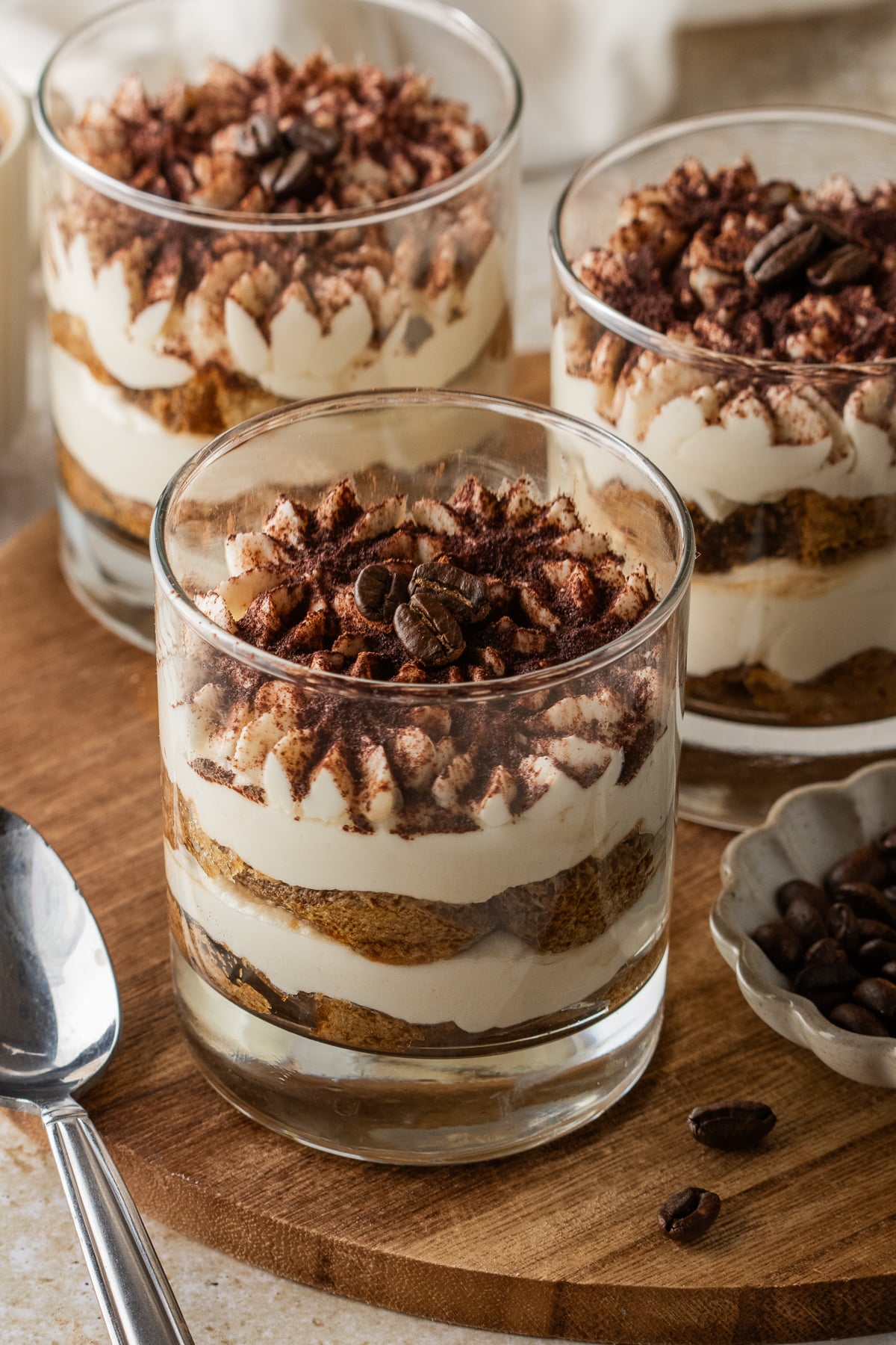 Three tiramisu cups on a board.