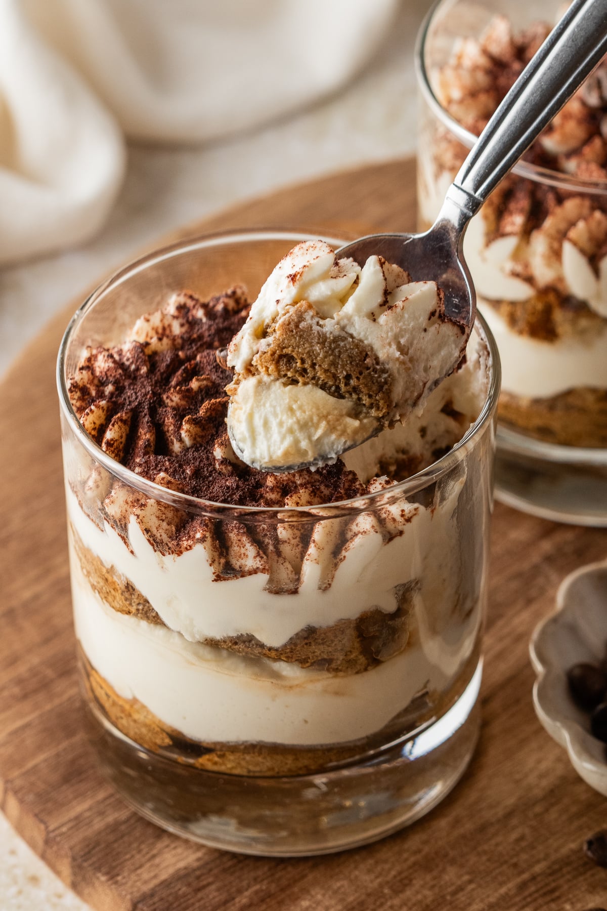 A spoon taking some tiramisu out of the cup.