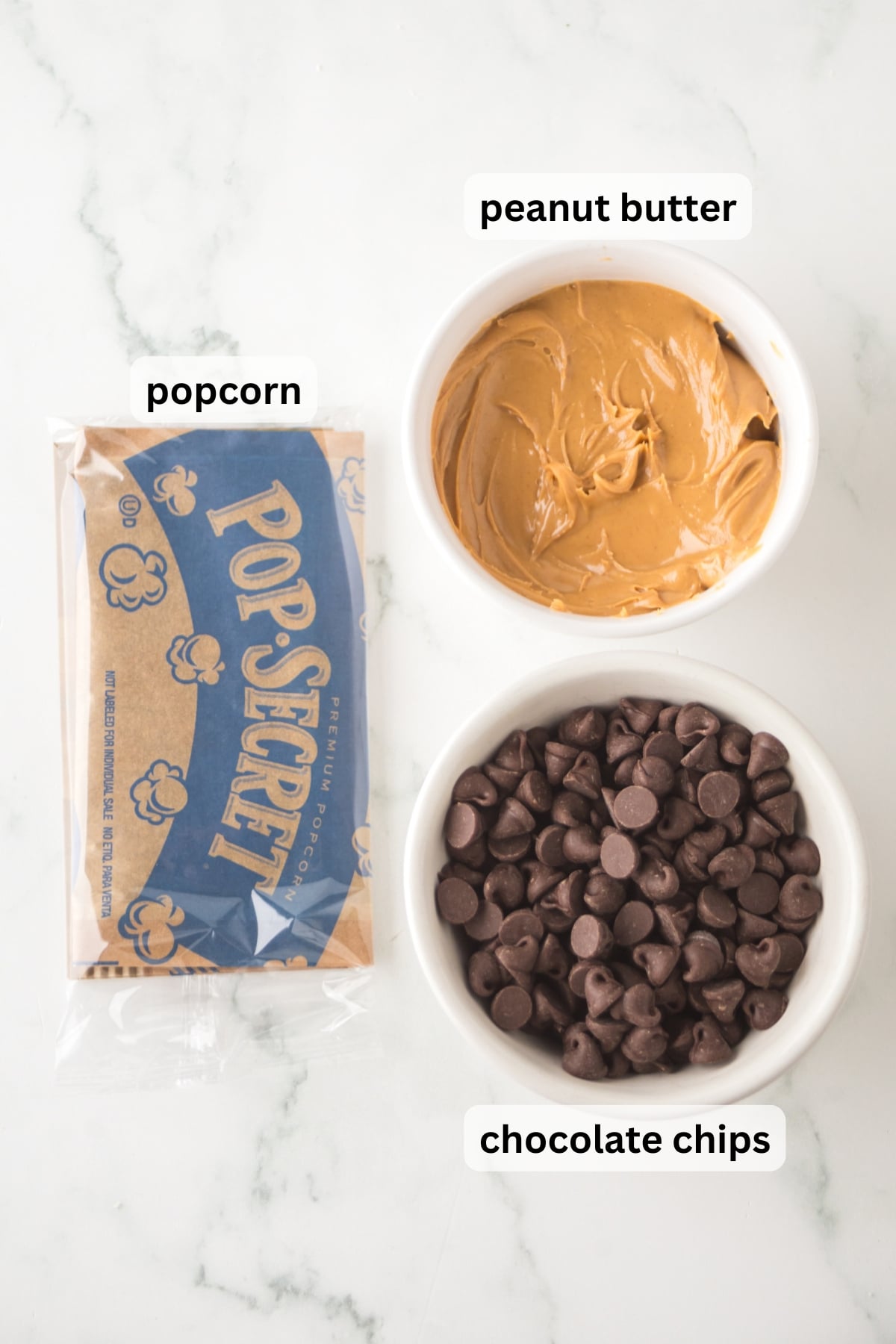 All of the ingredients needed to make chocolate peanut butter popcorn in bowls on a table