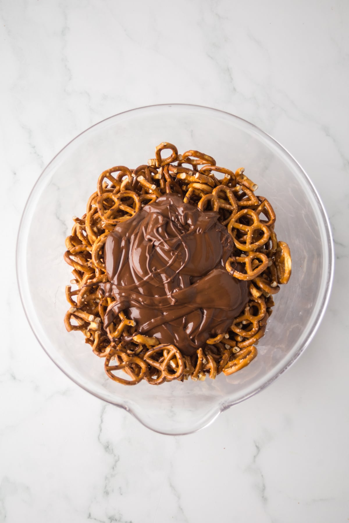 Melted peanut butter and chocolate mixture on top of pretzels in bowl.