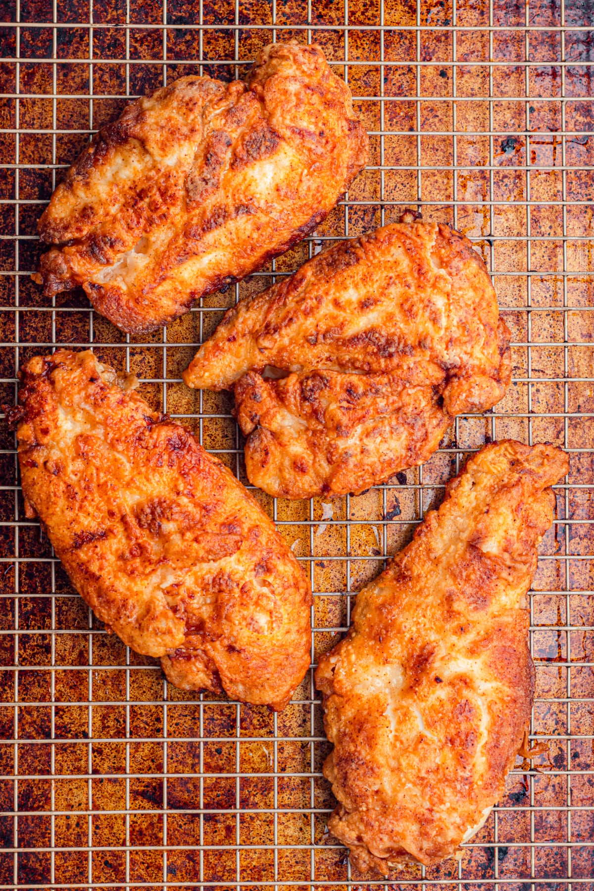 Cooked chicken on a wire rack to drain the oil.