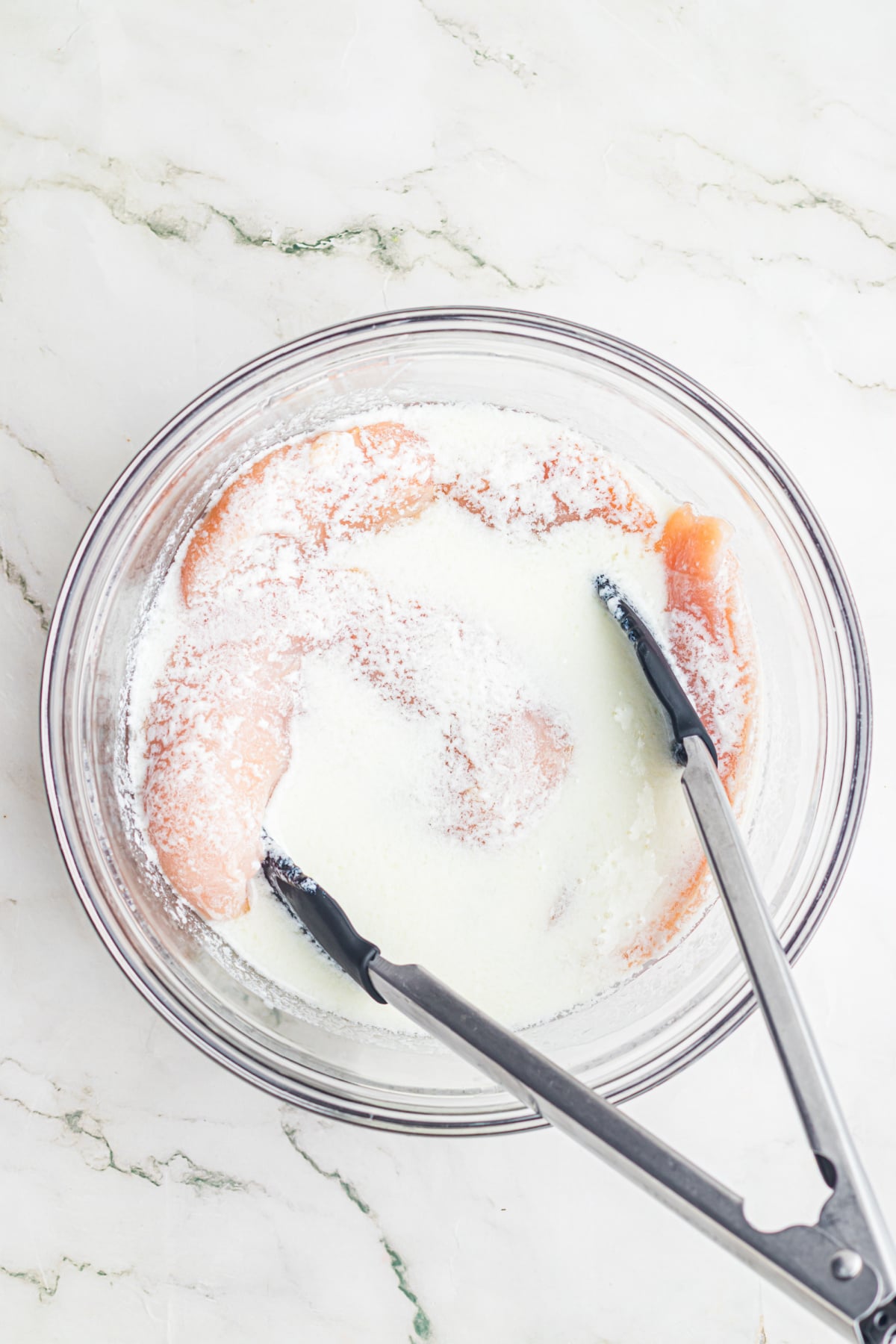 Chicken breasts in a bowl with buttermilk.