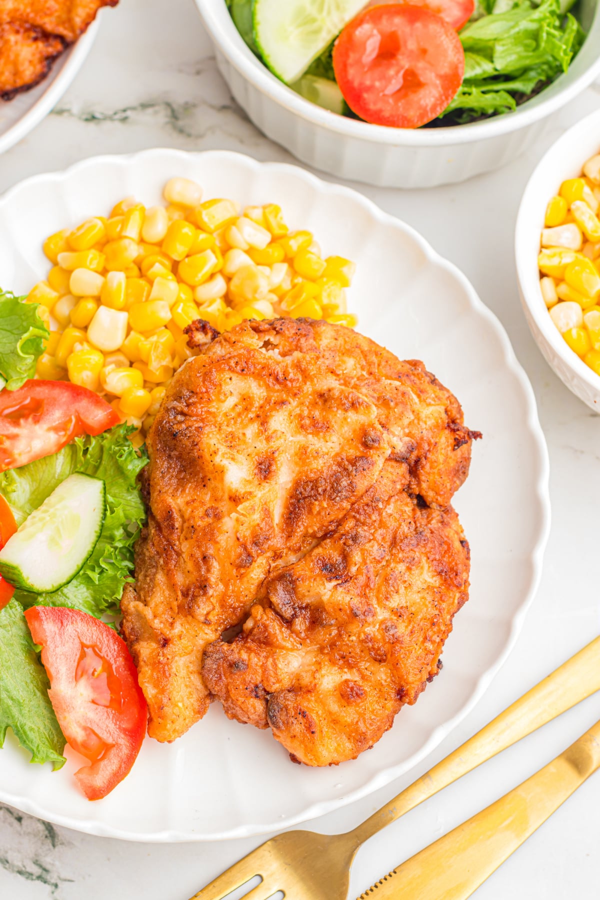 Fried chicken breast with corn and salad on the side.