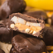 A pile of Peanut Butter Pretzel Bites on parchment on a table with the top one cut in half