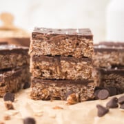 three peanut butter oatmeal bars stacked on a parchment covered table
