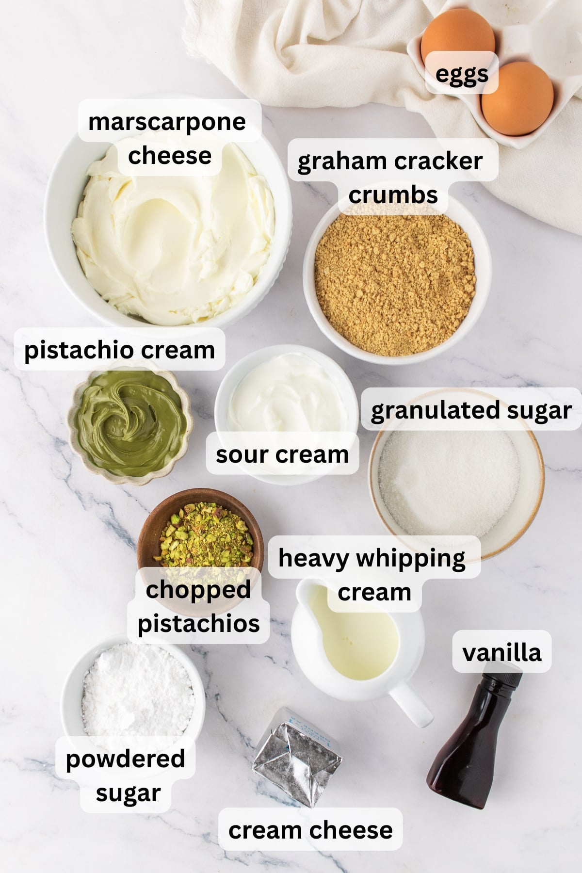 Ingredients to make pistachio cheesecakes in bowls on a table.