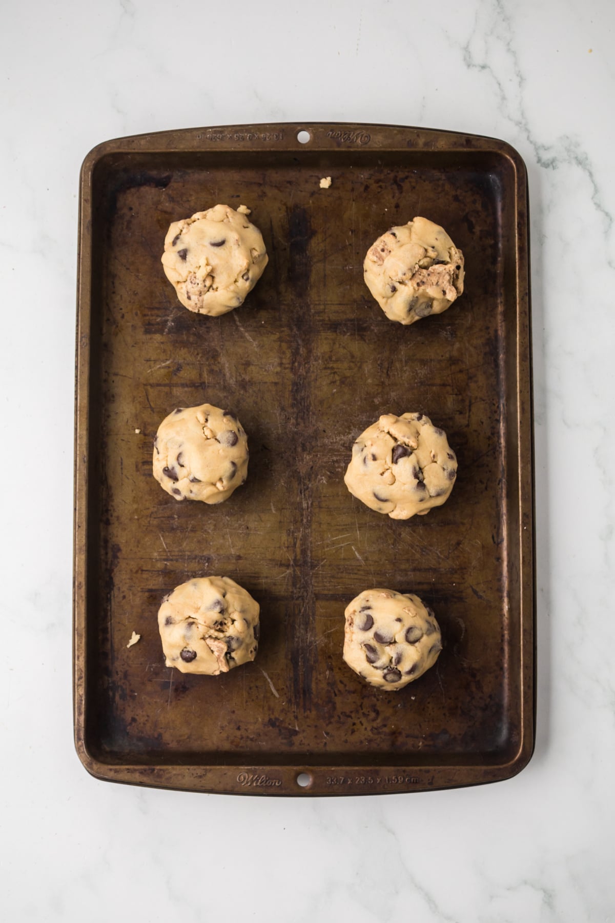 The dough scooped onto the baking sheet, and a marshmallow placed in the center of the dough.