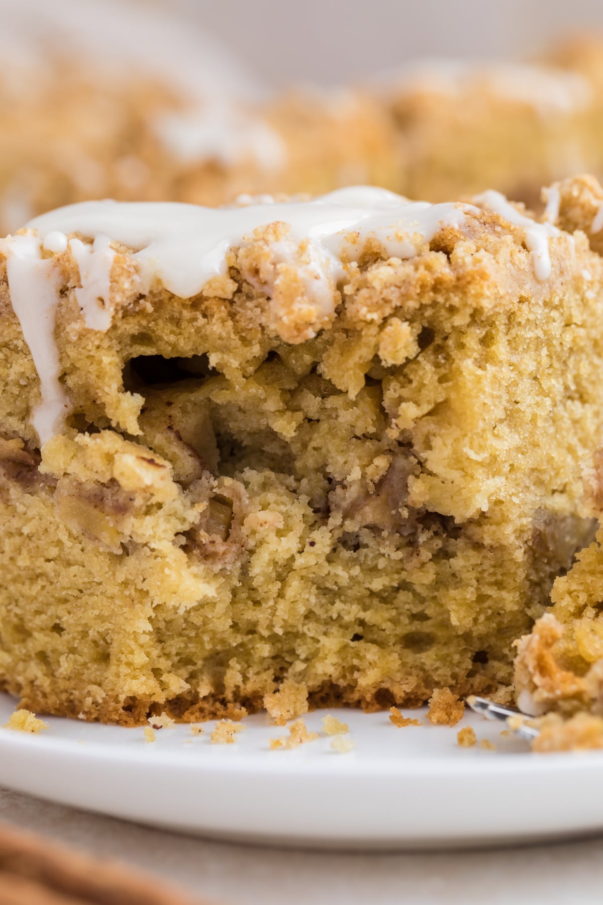 Cake drizzled with vanilla glaze and sliced on a plate missing a bite.