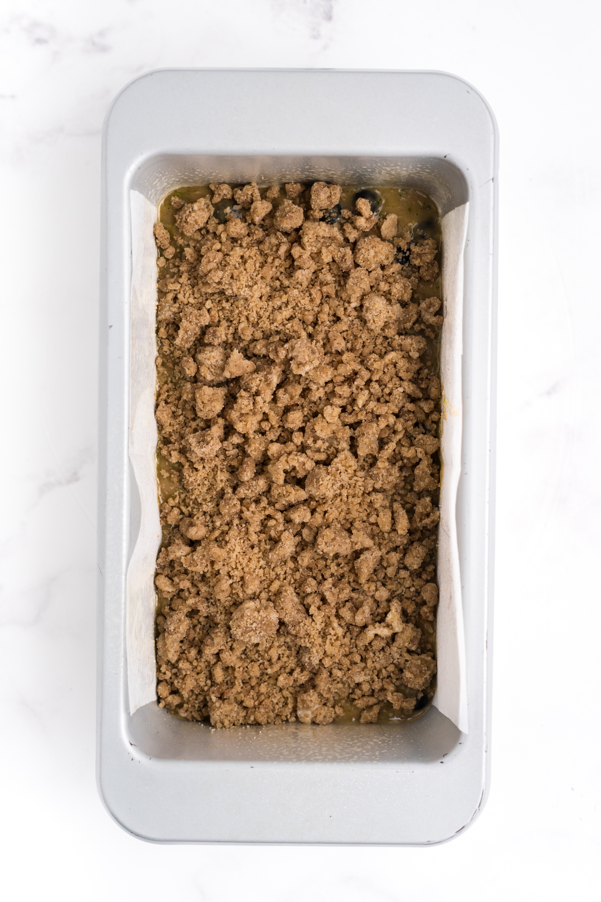 A loaf topped with crumble ready to bake.