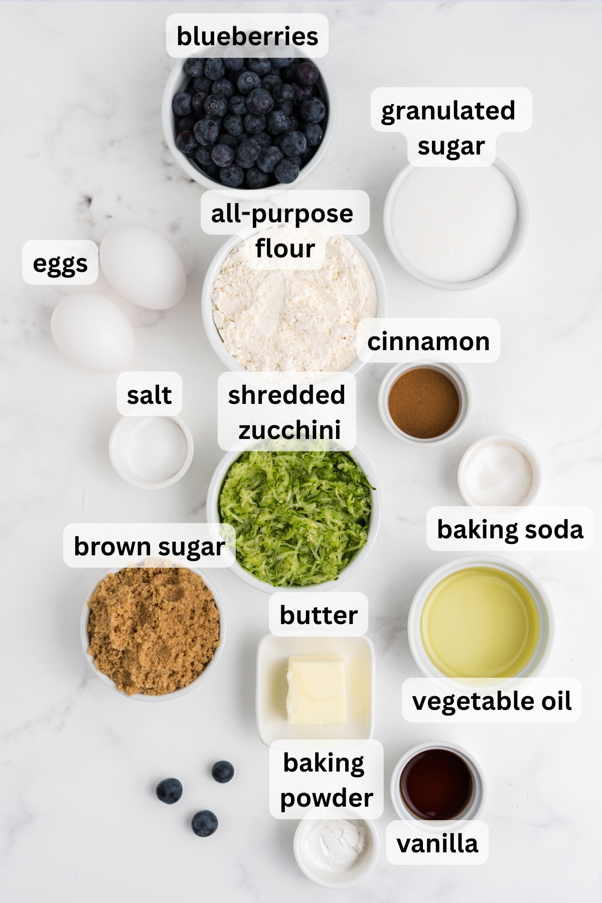 All of the ingredients needed to make Blueberry and Zucchini Bread in bowls on a table.