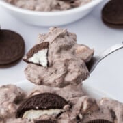 A spoonful of Cookies and Cream Fluff held in the air above a bowl.