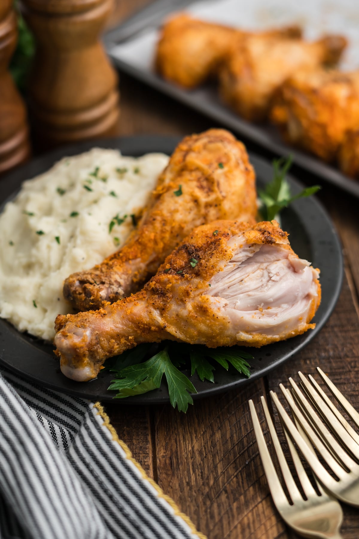 A crispy baked chicken drumstick with a bite taken out of it on a plate.