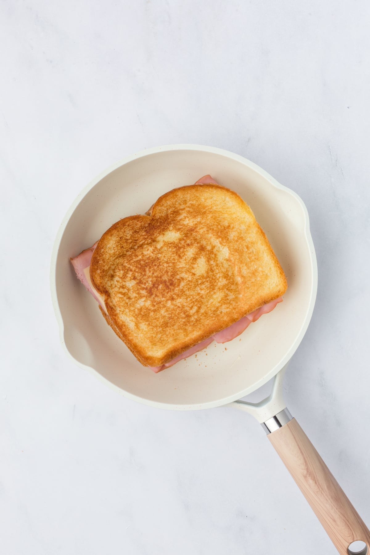 Grilled cheese sandwich flipped and browning on the second side.