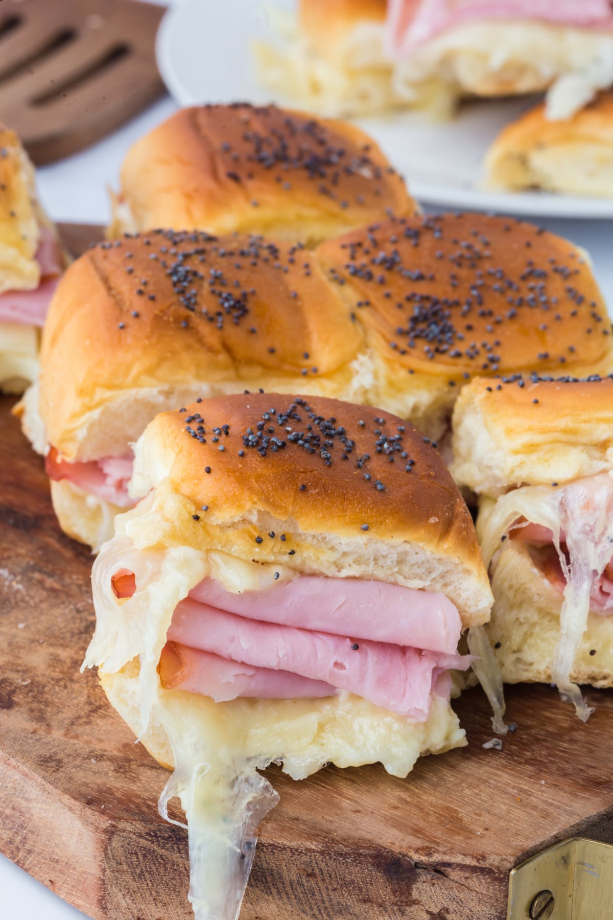 Ham and Swiss sliders with melted Swiss cheese on a cutting board.