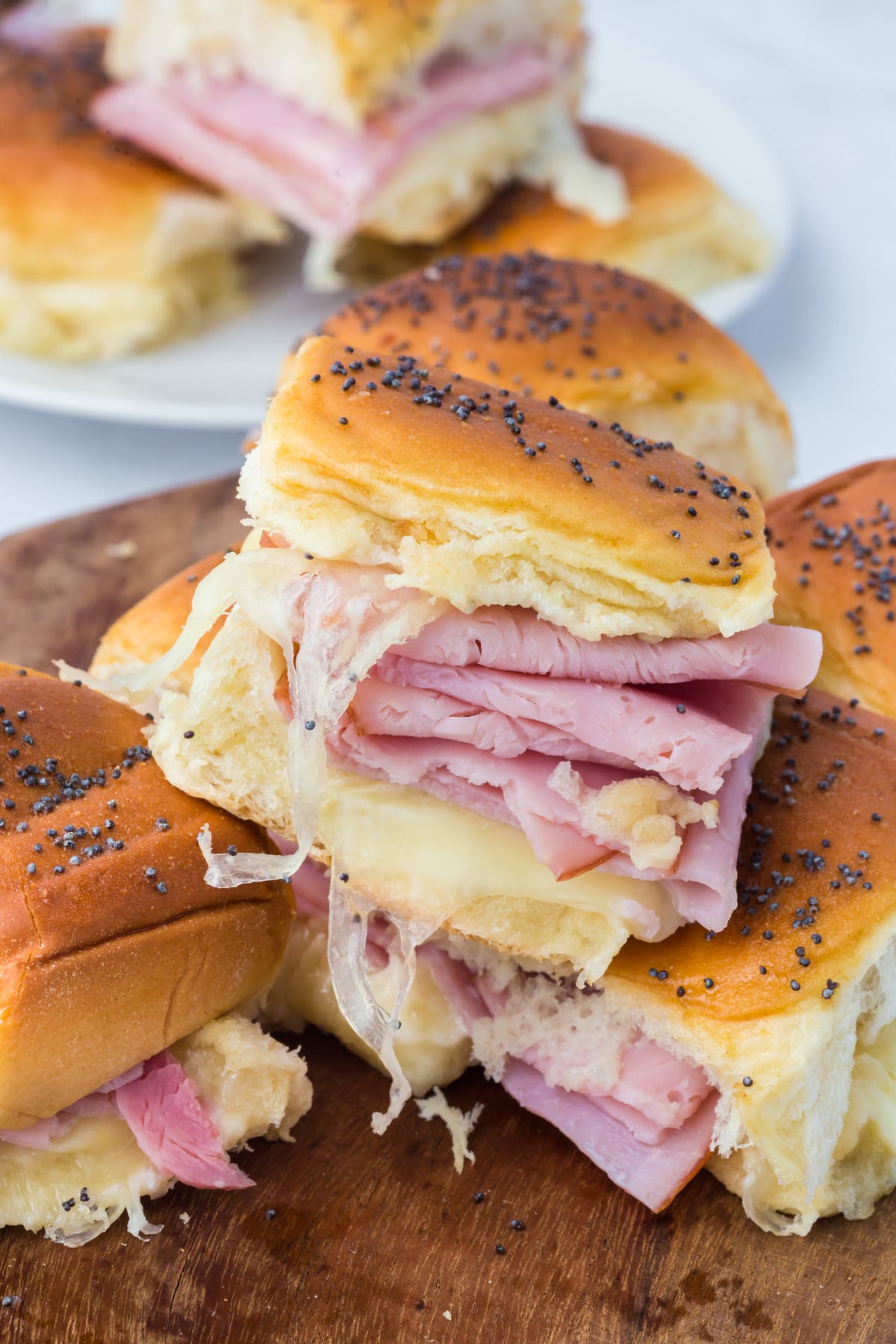 Slider with melted cheese on a Hawaiian roll on top of a few on a cutting board.