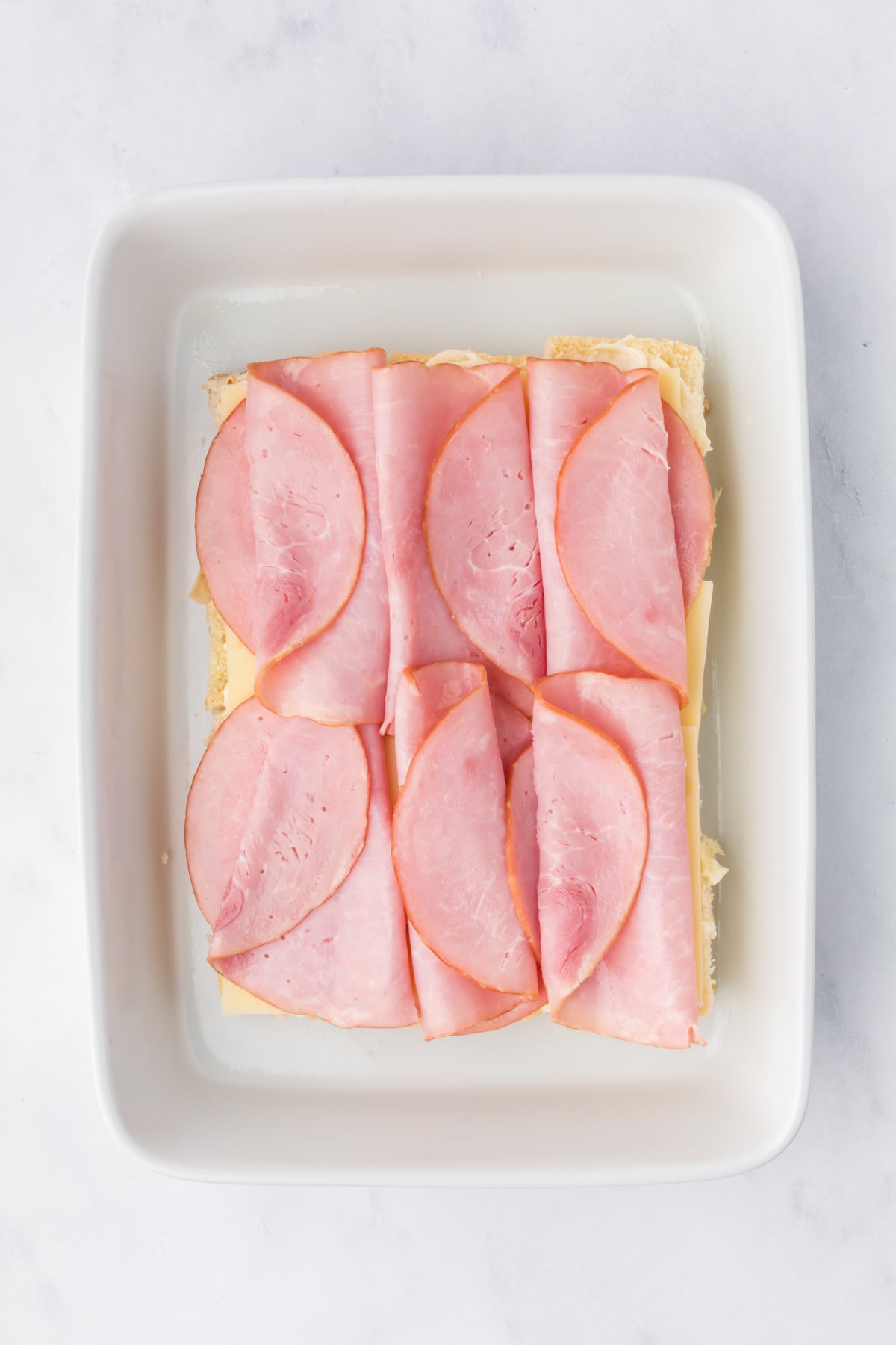 Sliced ham layered on top of Hawaiian rolls.