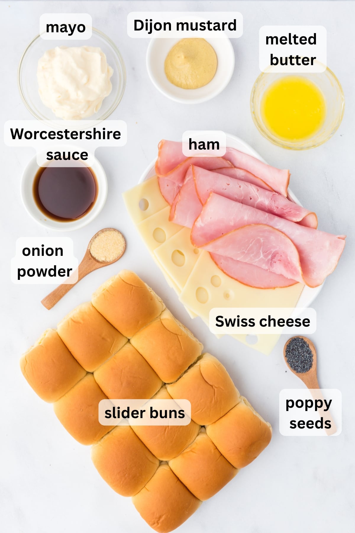 Ingredients needed to make ham and Swiss sliders arranged on a table in bowls.