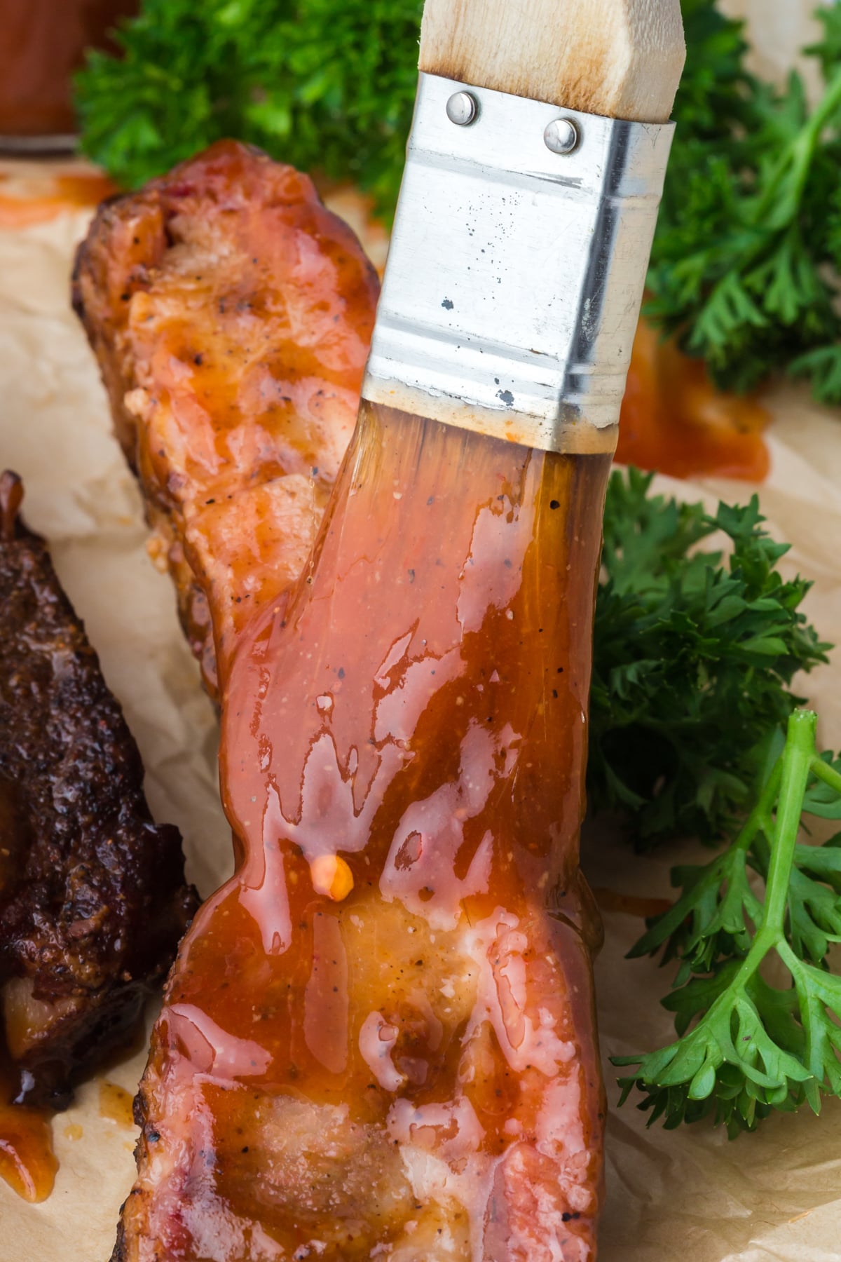 BBQ sauce being brushed onto pork ribs while cooking.