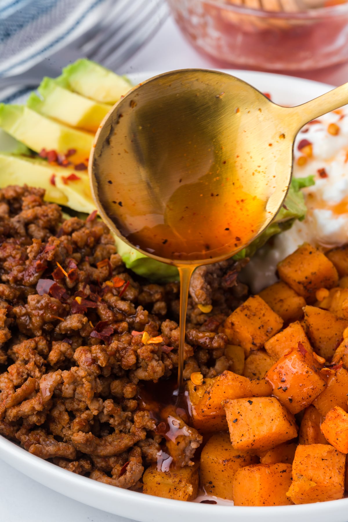 Hot honey being drizzled with a spoon all over the full bowl.