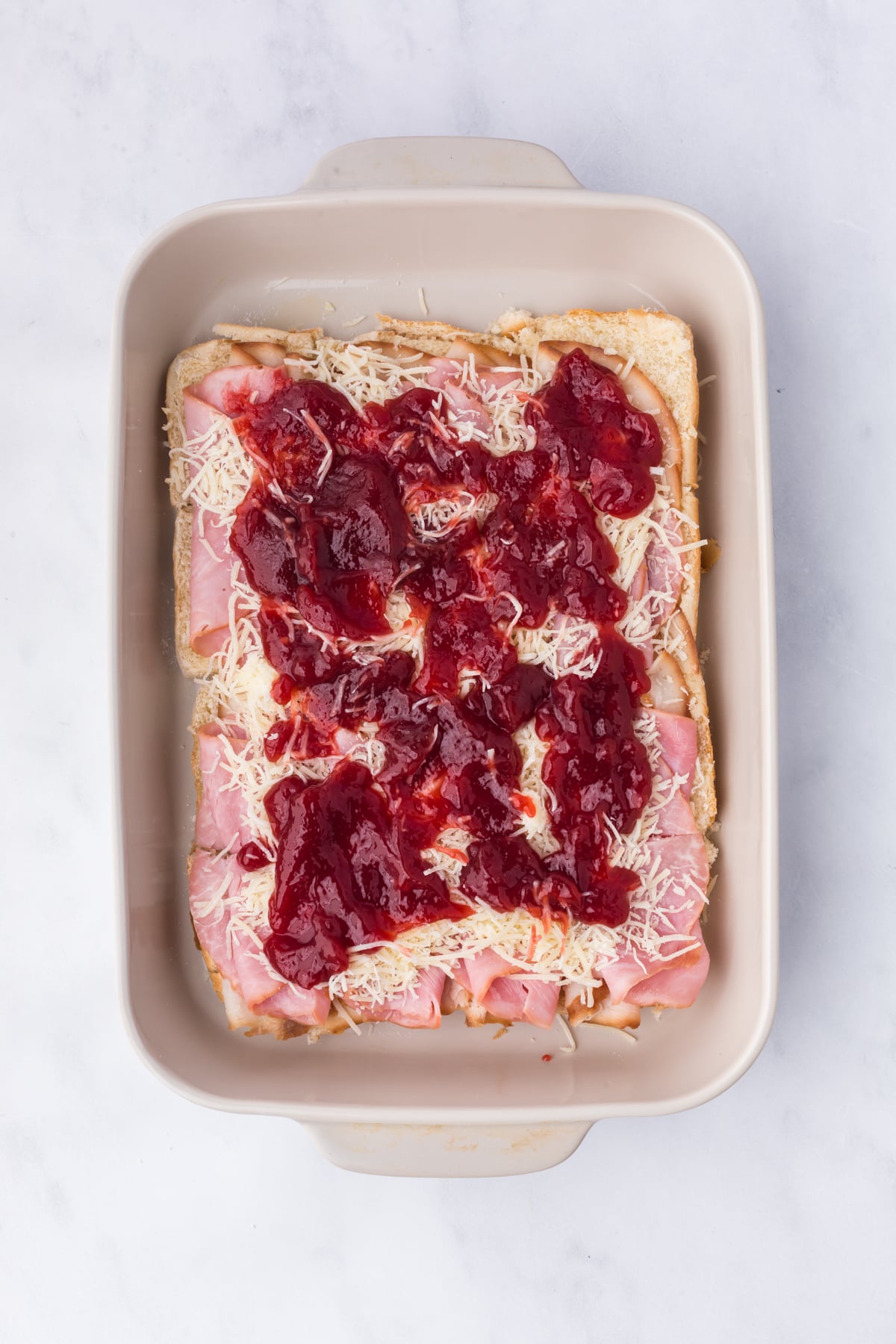 Raspberry jelly spread over Swiss cheese before adding slider tops.