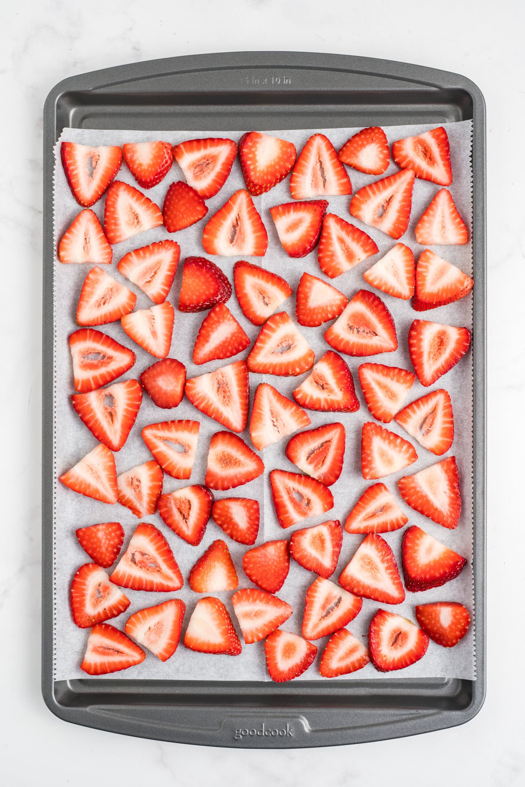 Sliced strawberries on a baking sheet.