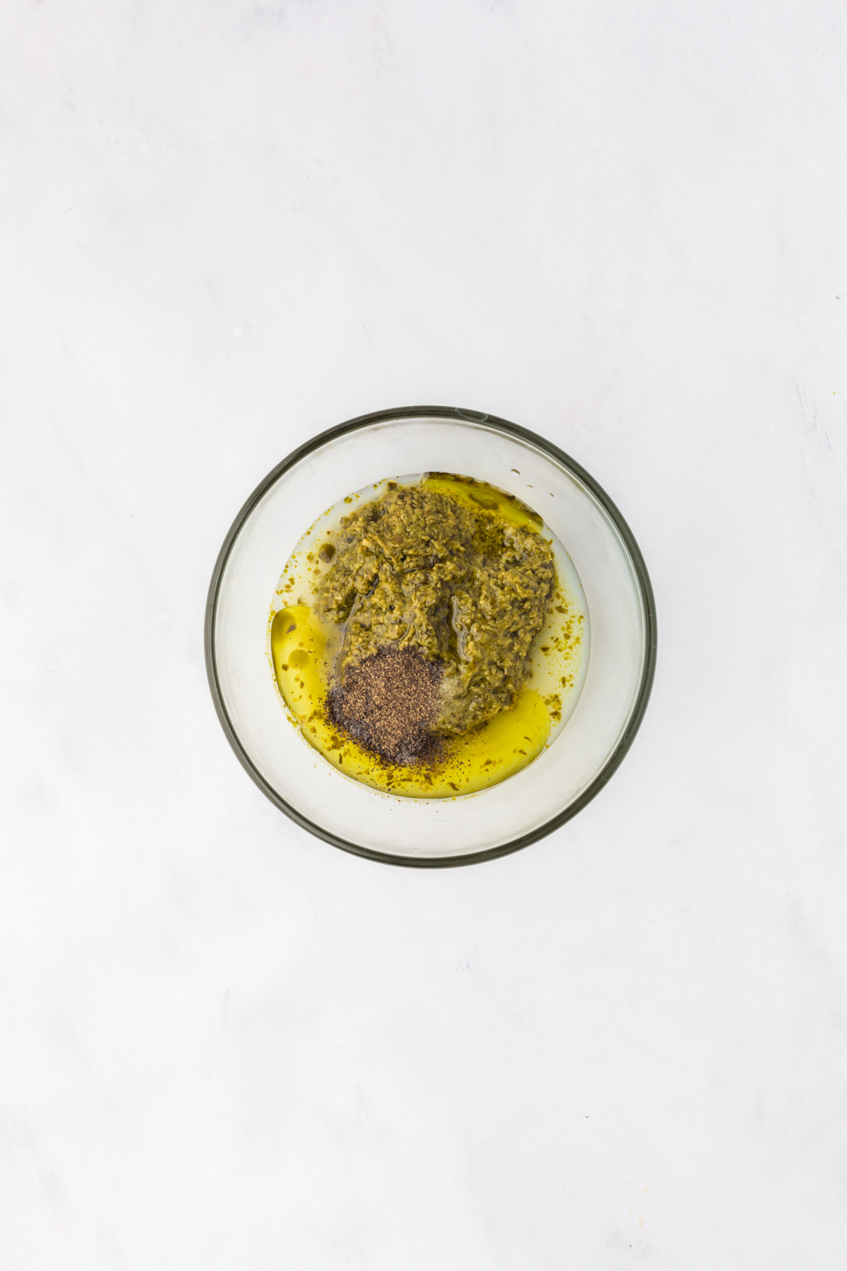 A bowl full of basil pesto, lemon juice, olive oil, salt, and pepper.