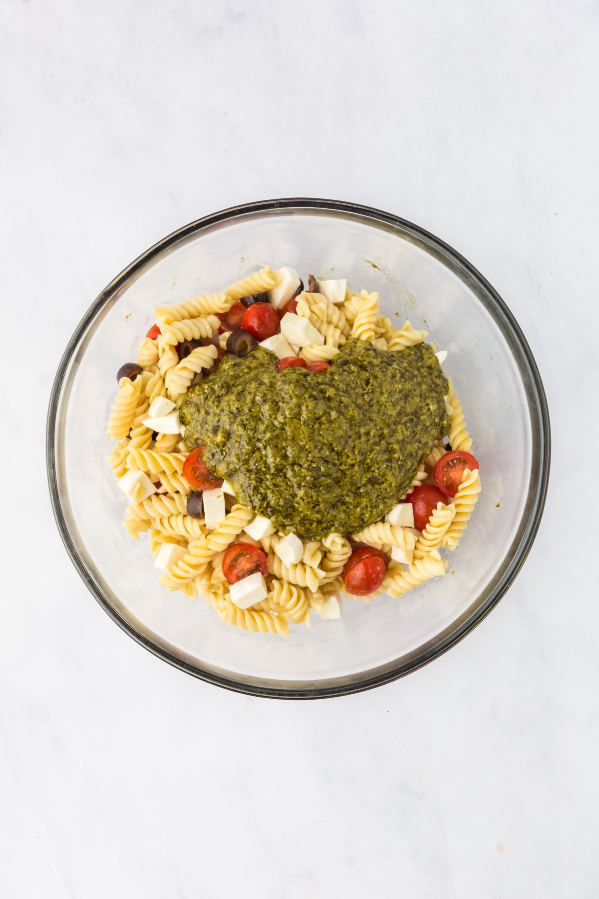 The pesto mixture added to the pasta mixture.