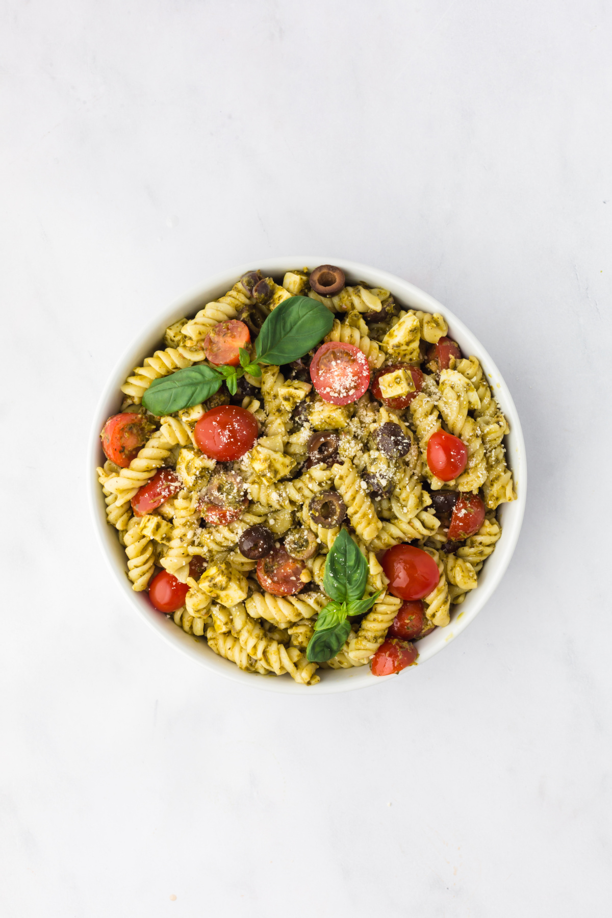 The pesto mixture tossed and coating all of the ingredients in the bowl.