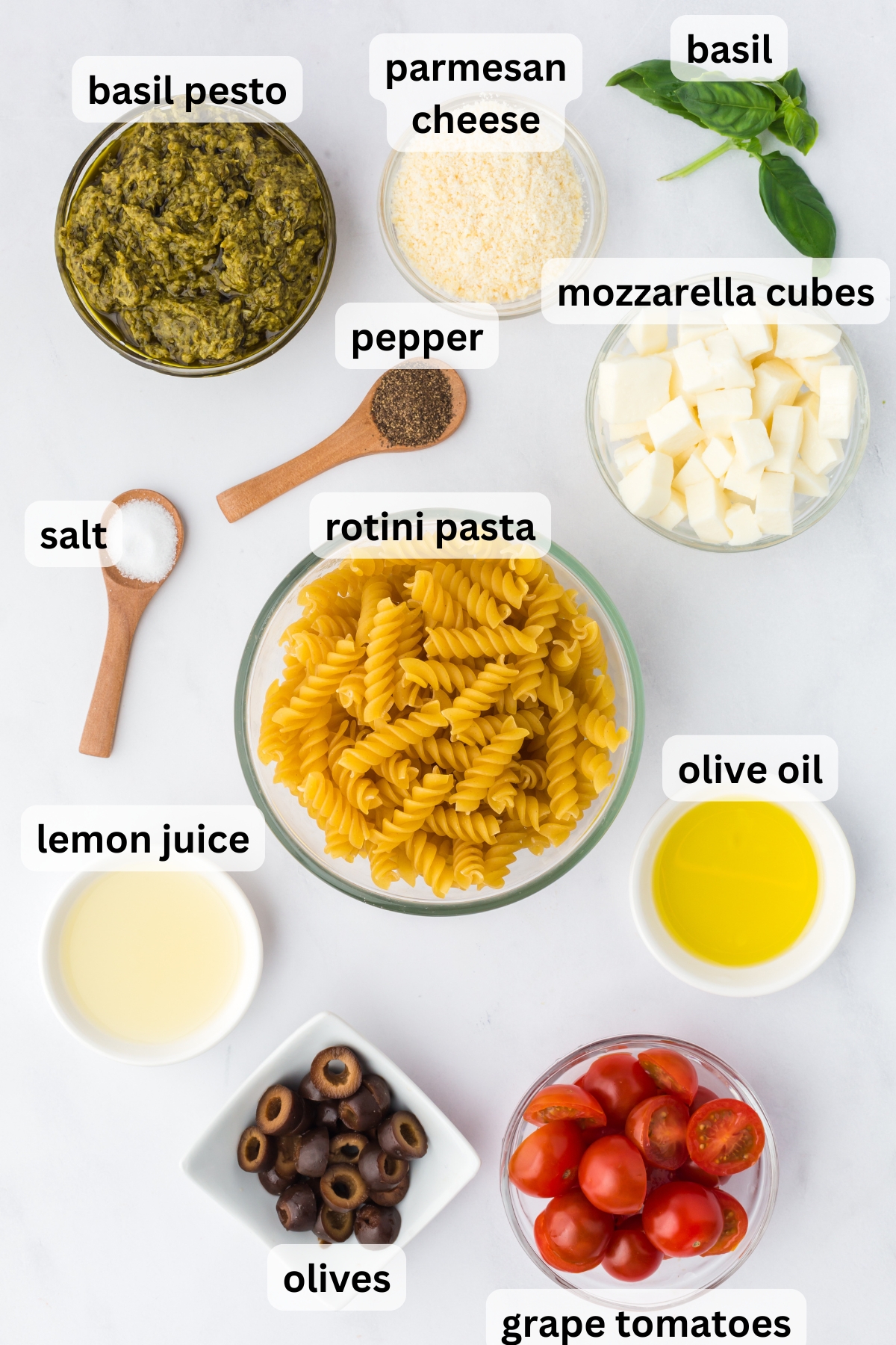 All of the ingredients needed to make Pesto Pasta Summer Salad in bowls on a table.