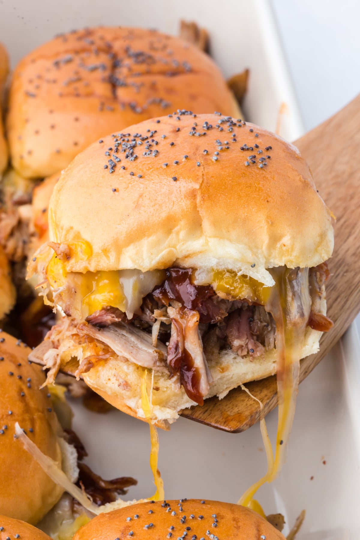 A freshly baked slider being lifted out of the casserole dish with a spatula.