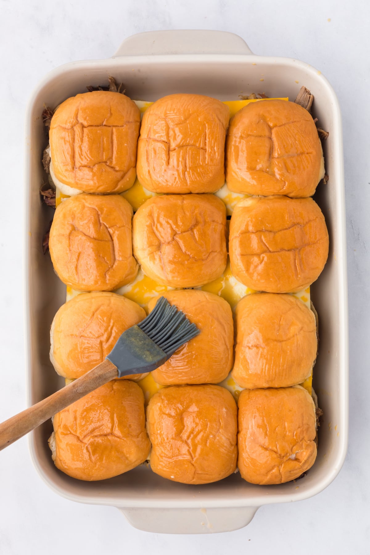 A brush with melted butter and Worcestershire sauce coating bun tops.