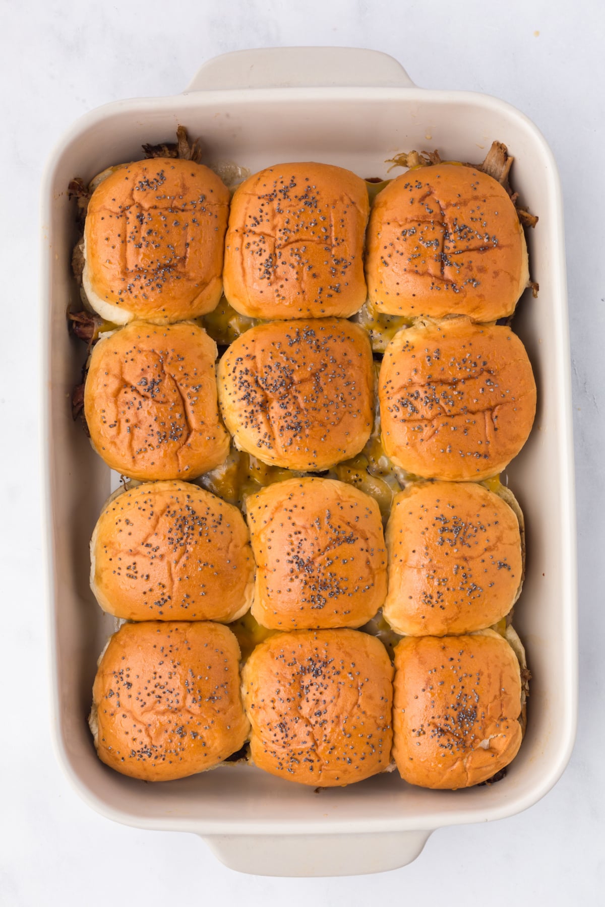 Baked sliders with poppyseeds in baking dish.