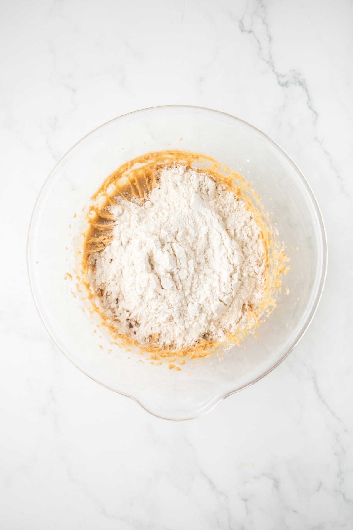 Flour and baking ingredients mixed into peanut butter cookie dough.