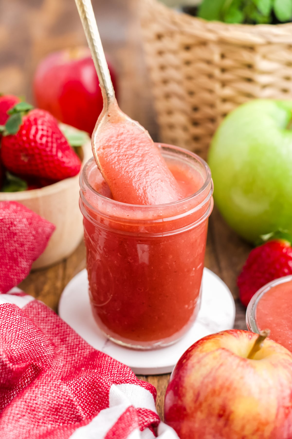 A spoonful lifting out of a jar full of applesauce.