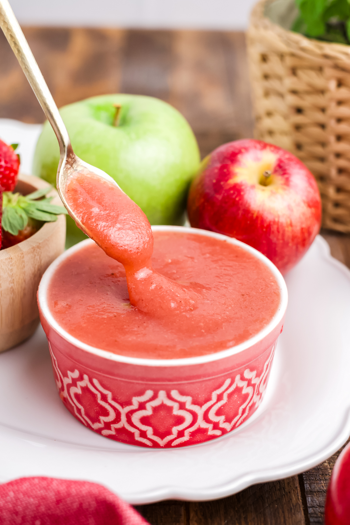 A spoonful lifting out of a bowlful of applesauce dripping off the spoon.