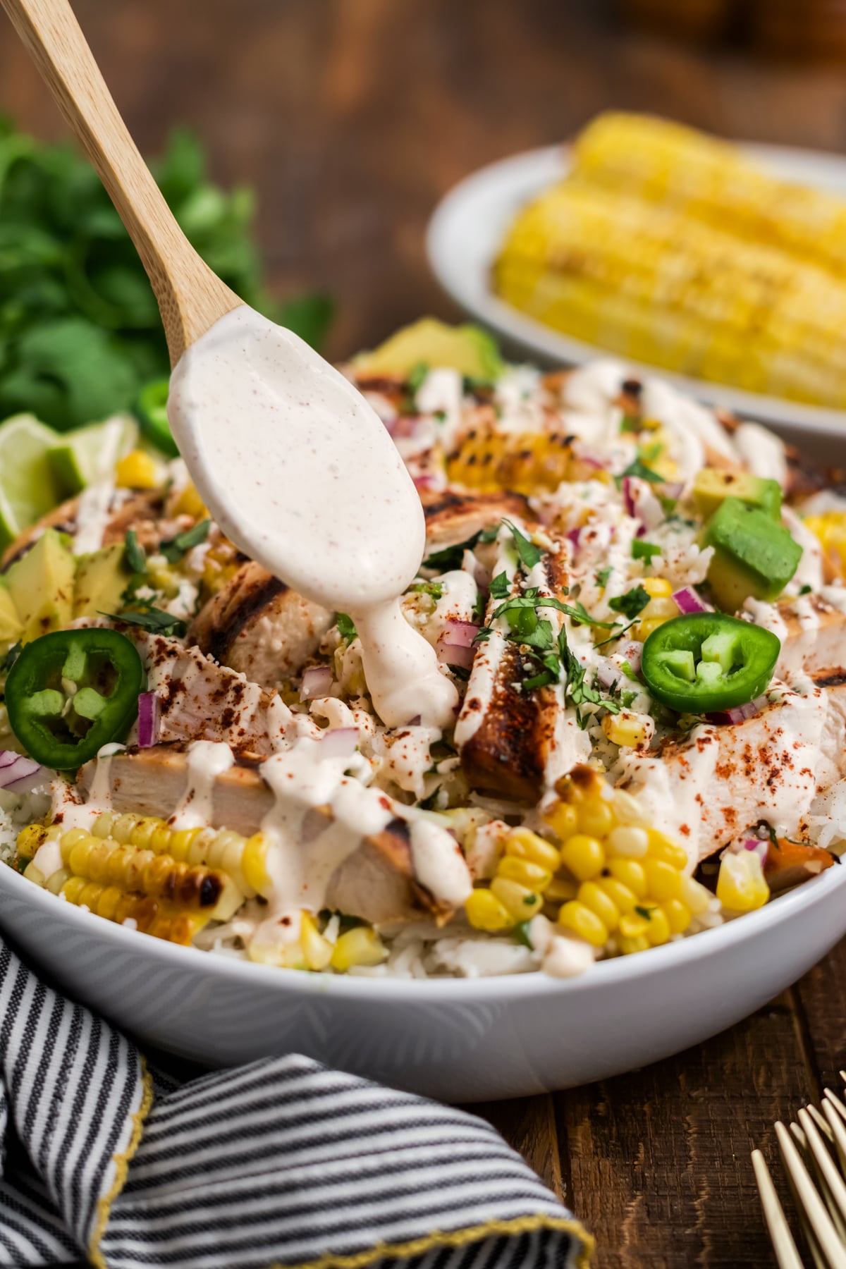 Dressing on a spoon dripping on a Rice Bowl.