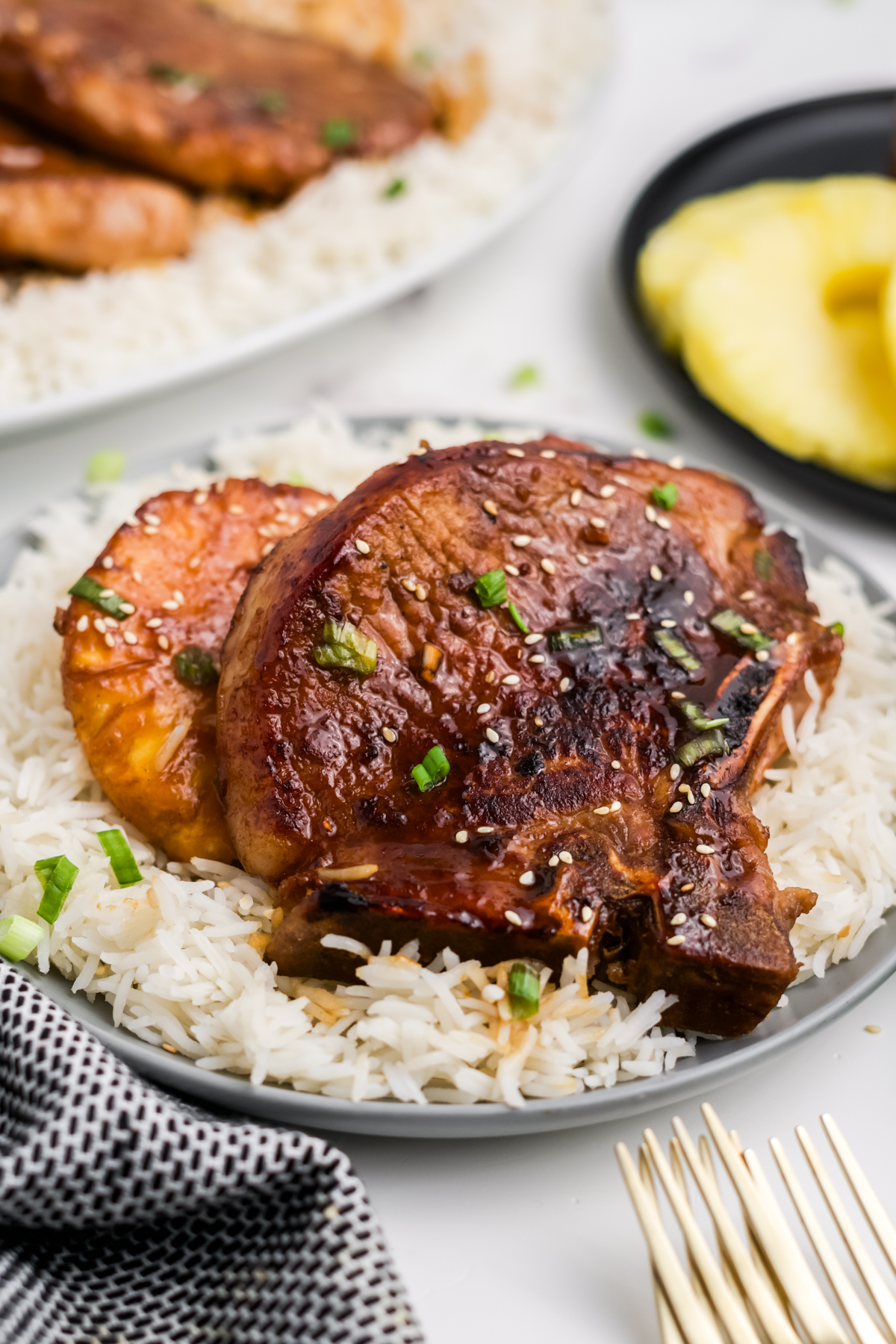 A pork chop and a slice of pineapple on a plate.