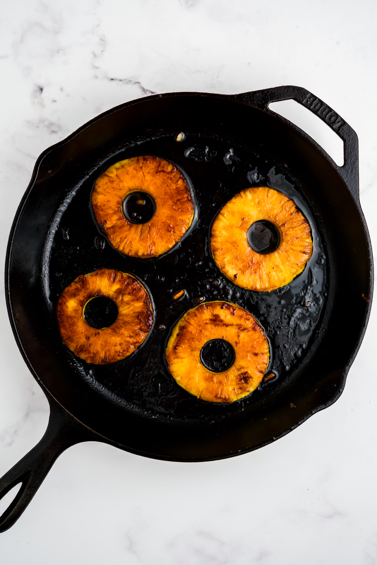 Pineapple slices searing on the cast iron.