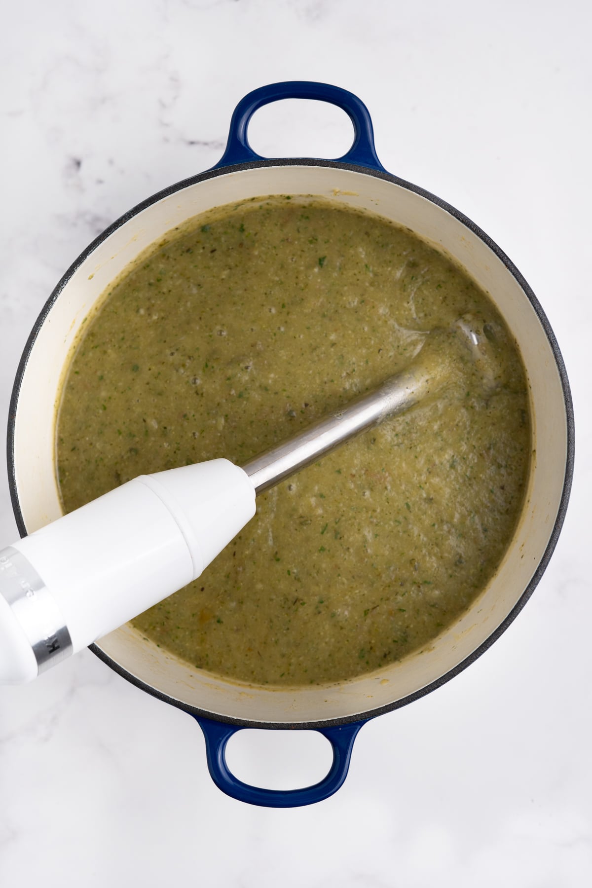 An immersion blender smoothing the soup.