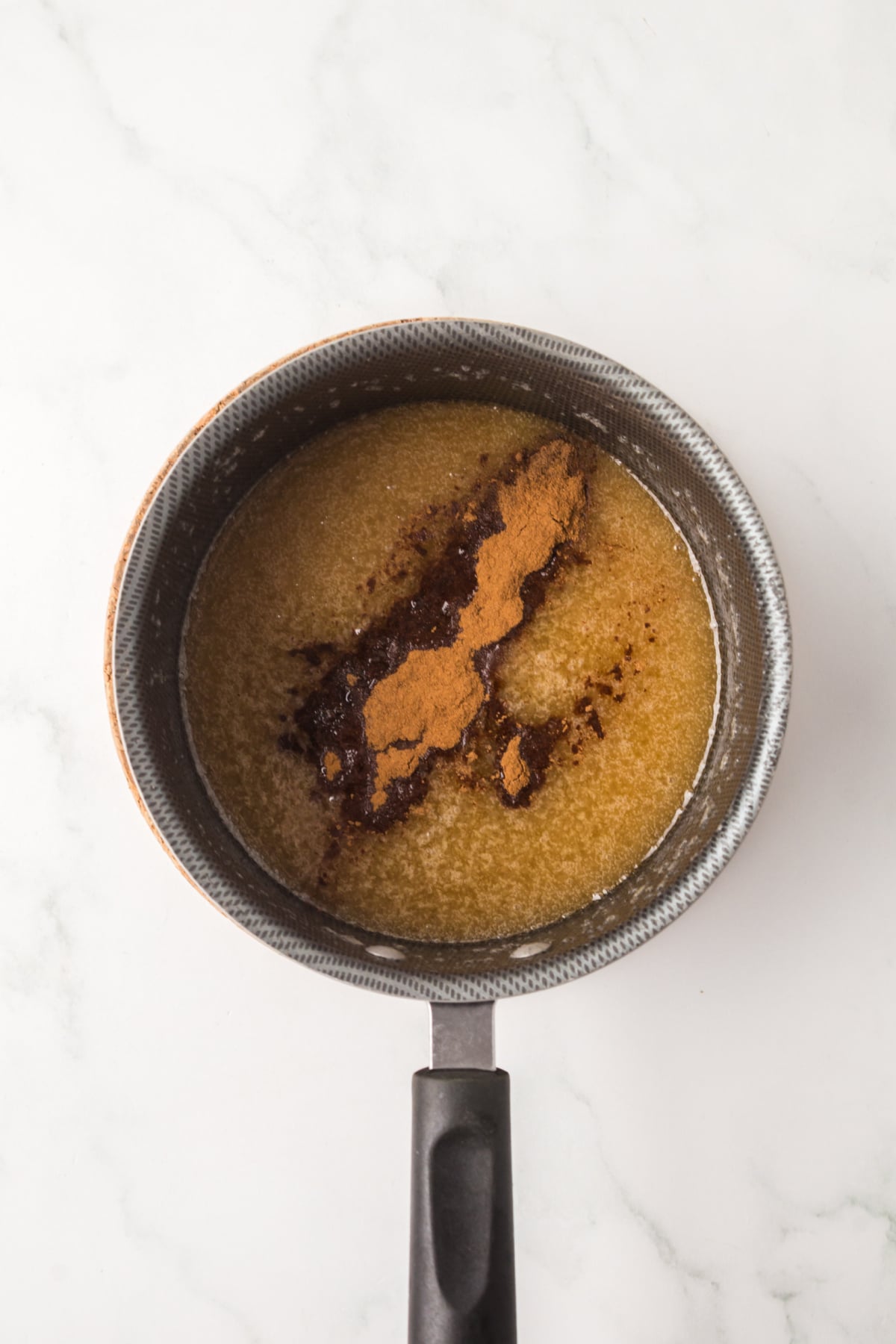 Butter toffee mixture finished simmering in a saucepan with cinnamon and nutmeg added. 