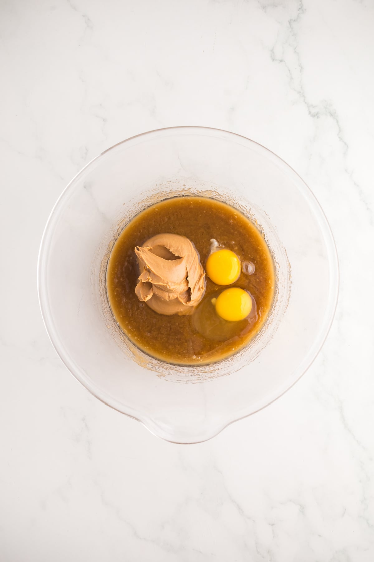 A bowl full of melted butter, brown sugar, peanut butter and eggs.