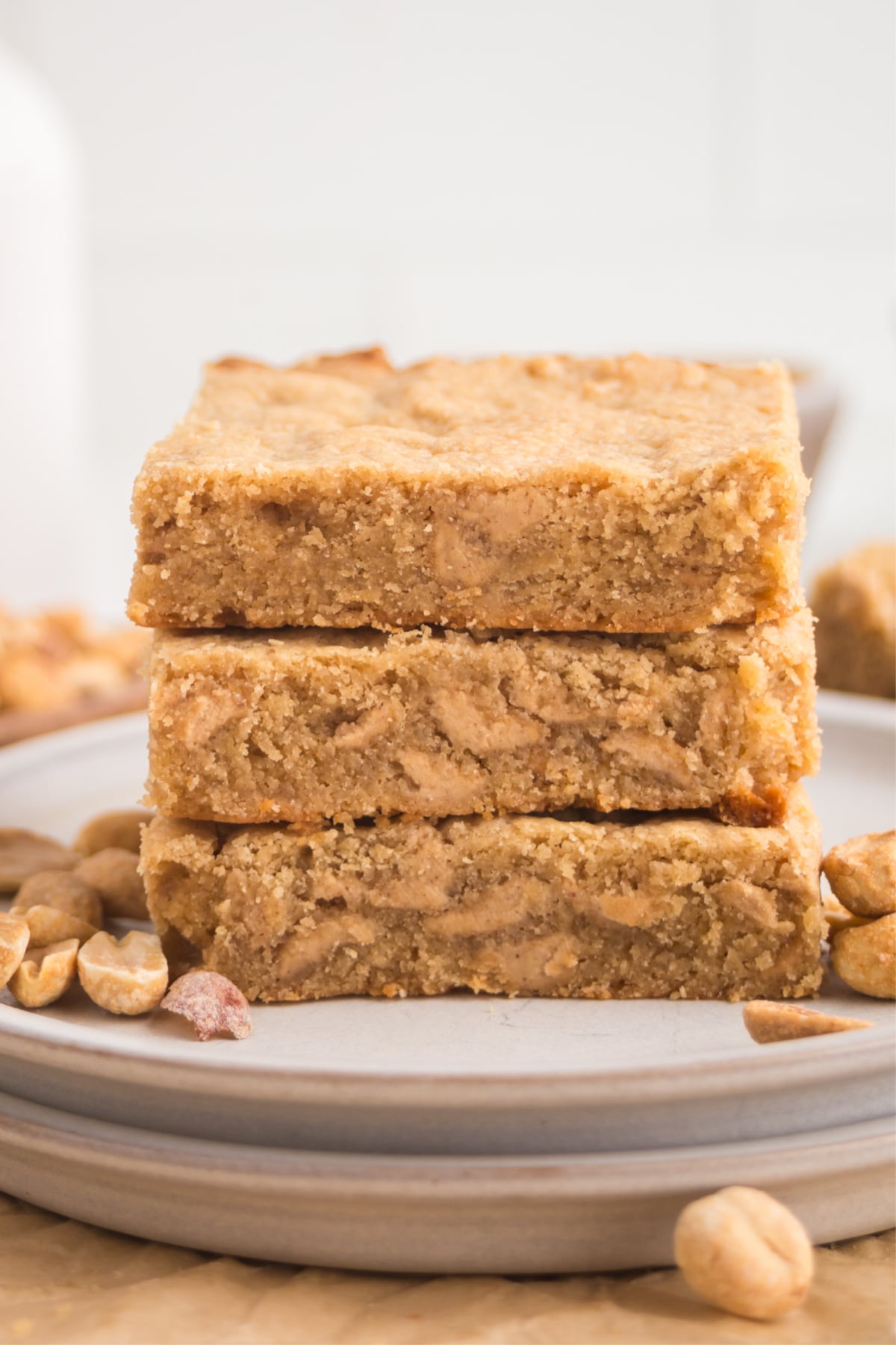 A stack of blondies on a plate with some peanuts.