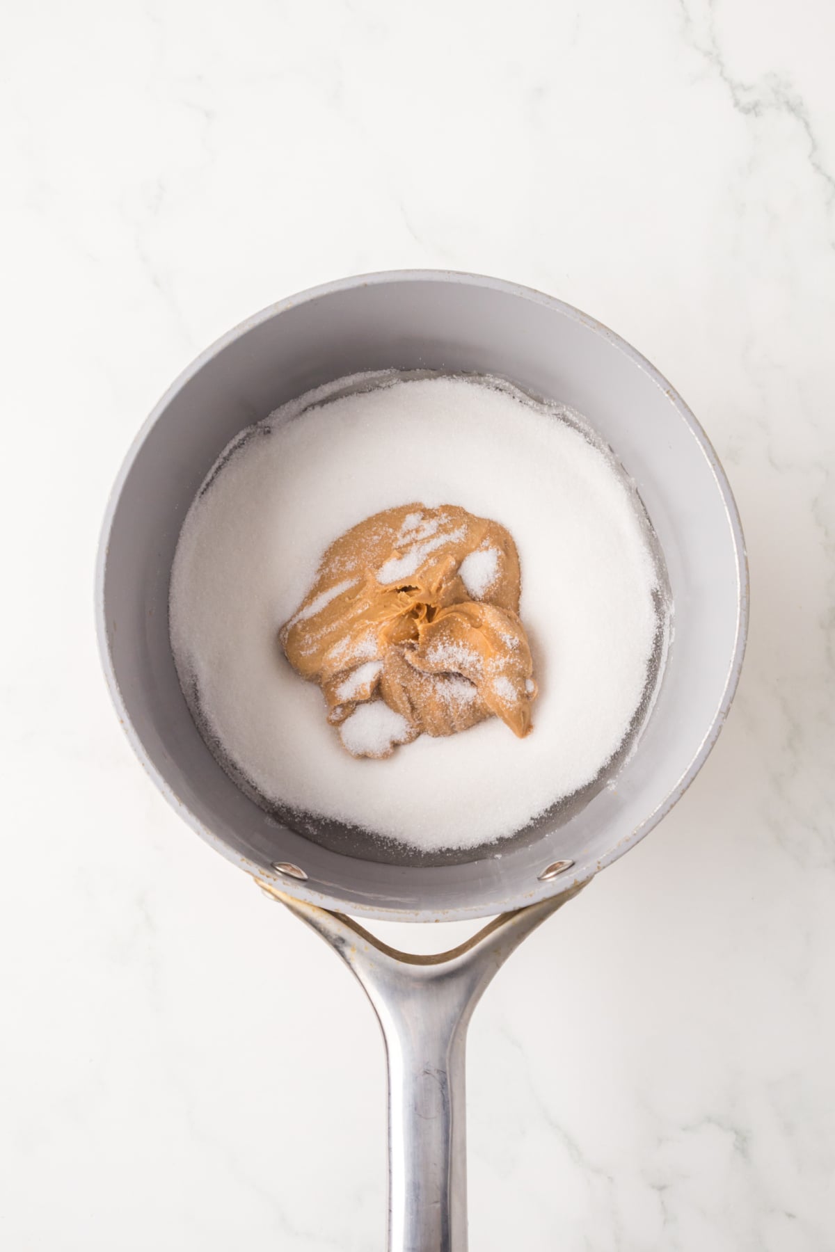 Peanut butter, sugar, and corn syrup mixture heating in a saucepan.