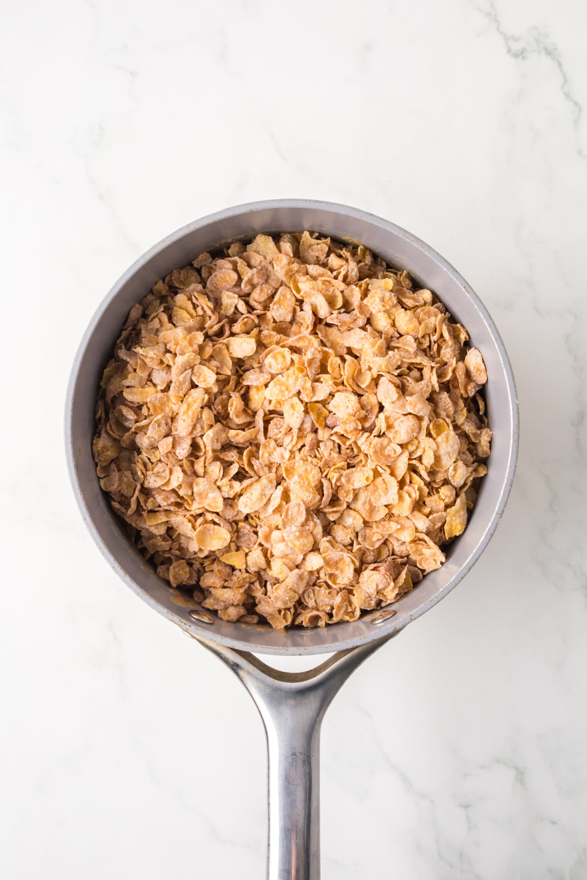 Frosted Flakes being stirred into the warm peanut butter mixture.