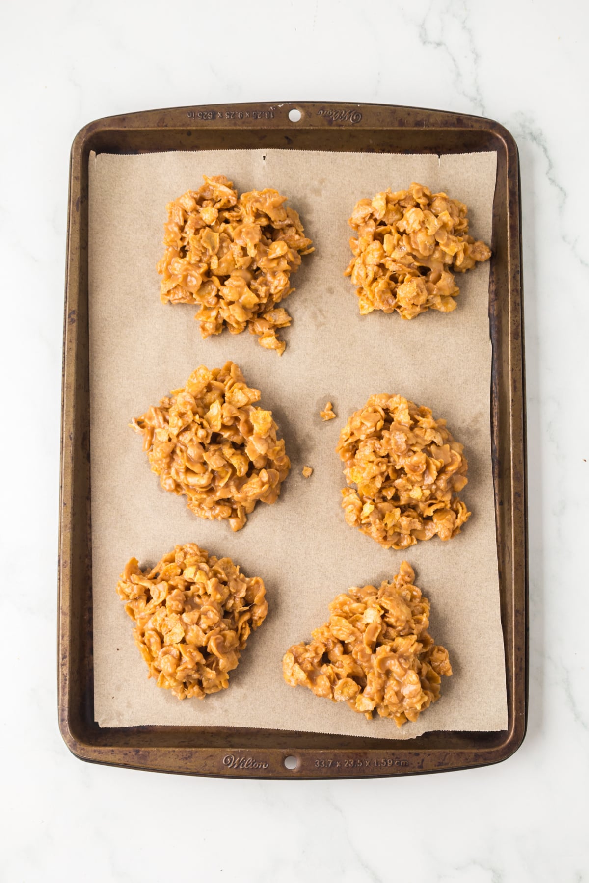 Cookies scooped onto parchment paper lined baking sheet to cool.