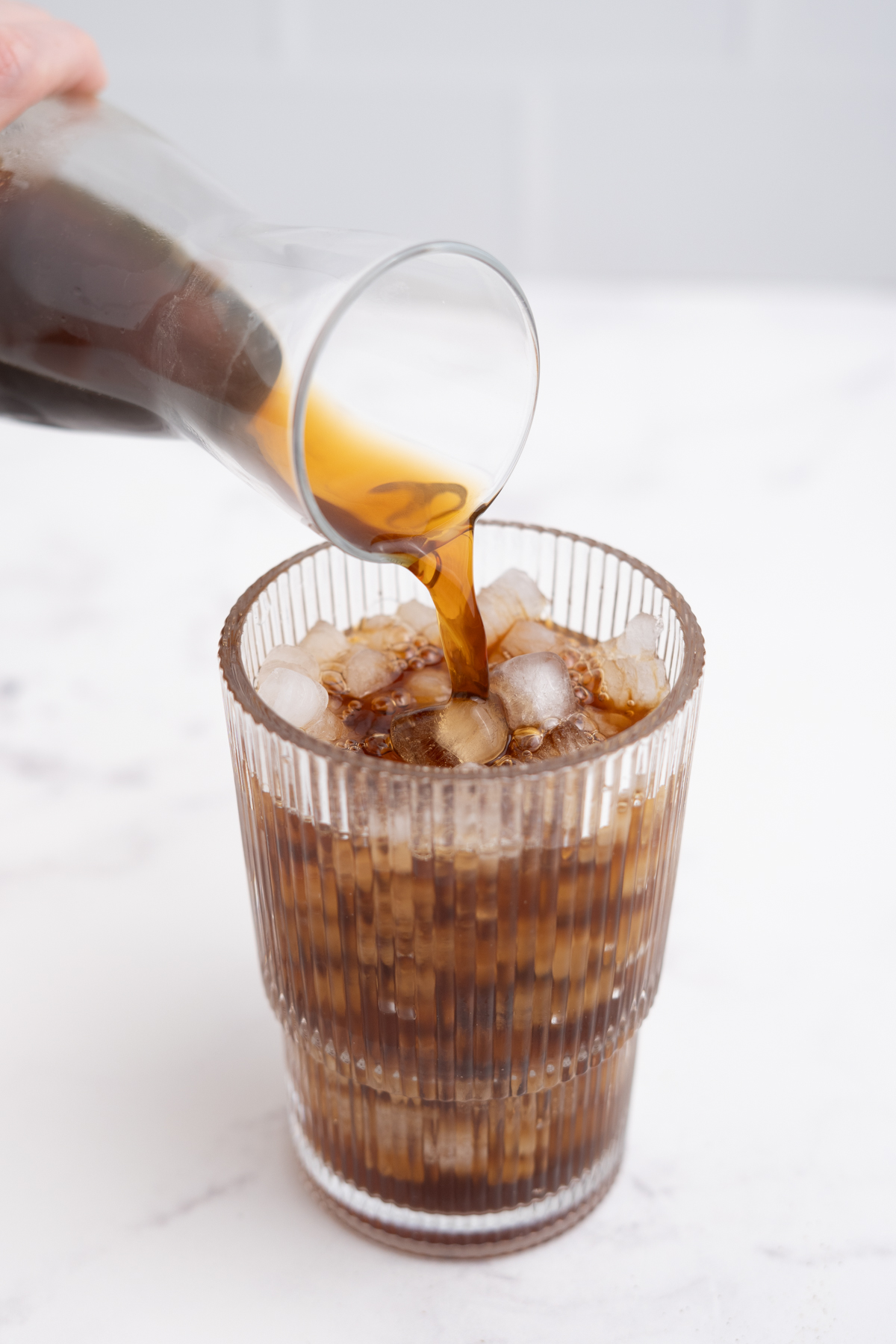 A tall glass filled halfway with ice with cold brew coffee poured on top.