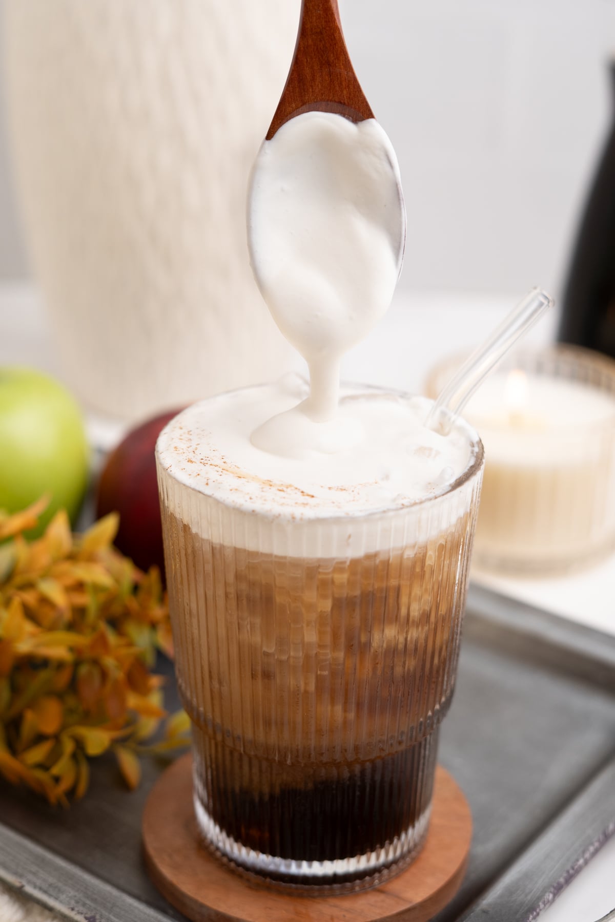 A glass of apple crisp cold brew with cold foam being drizzled on top.