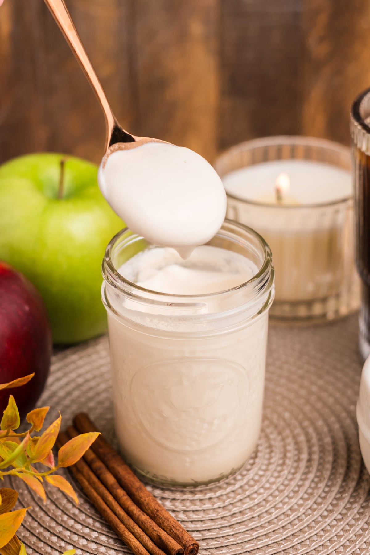A spoon lifting homemade Apple Crisp Cold Foam from a mason jar.